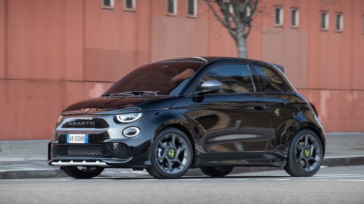 Black Abarth 500e parked in front of a terracota coloured building