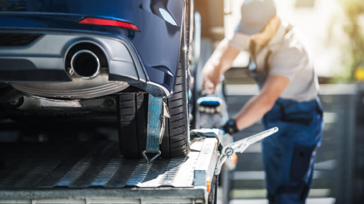 Delivery driver unclasping the straps on a car