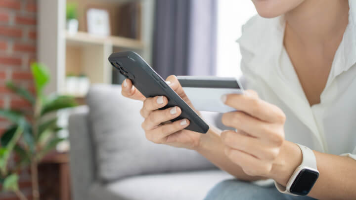 Close up of someone holding a smartphone in one hand and a payment card in the other hand