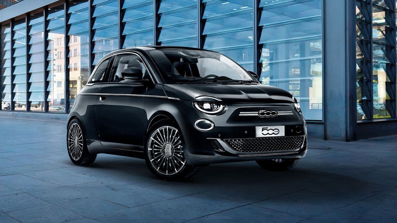 Black Fiat 500e parked in front of a building with glass walls
