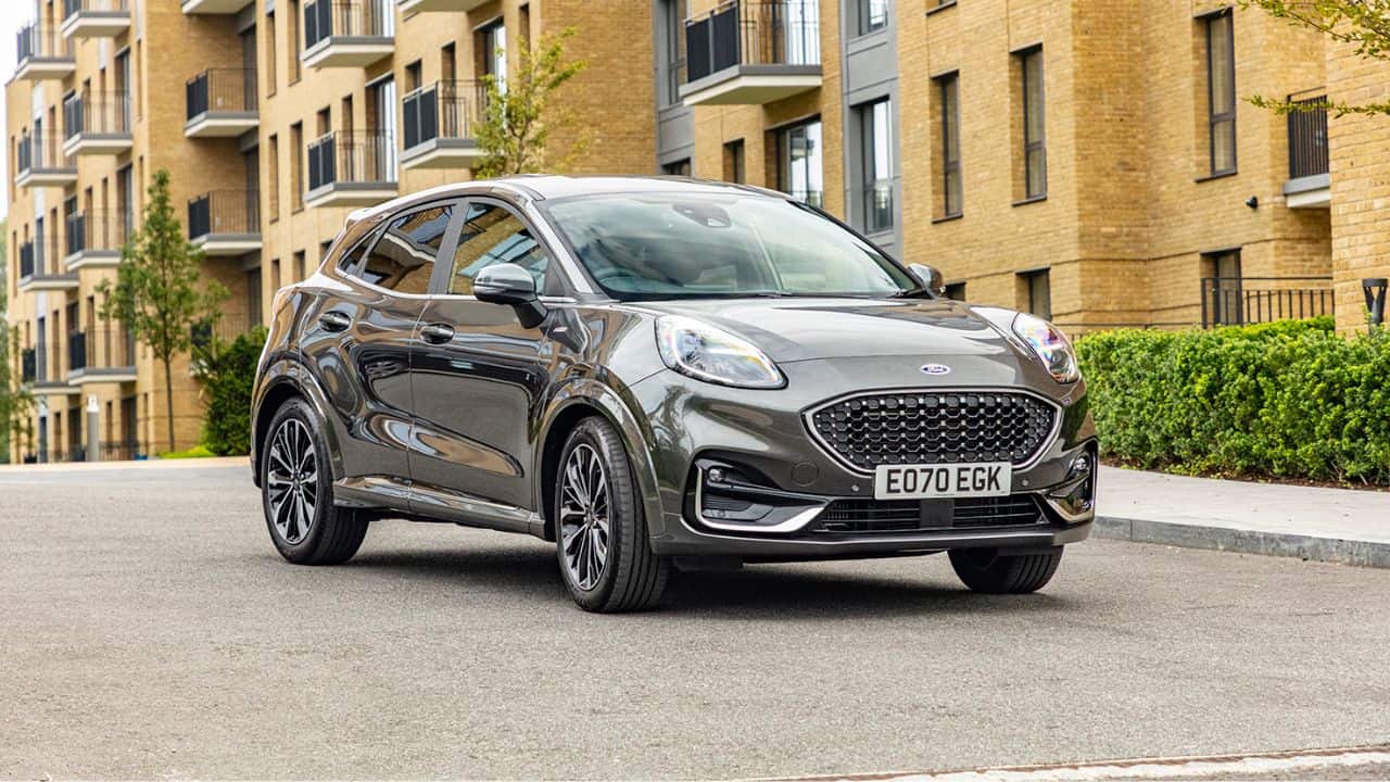 Grey Ford Puma parked in front of several buildings