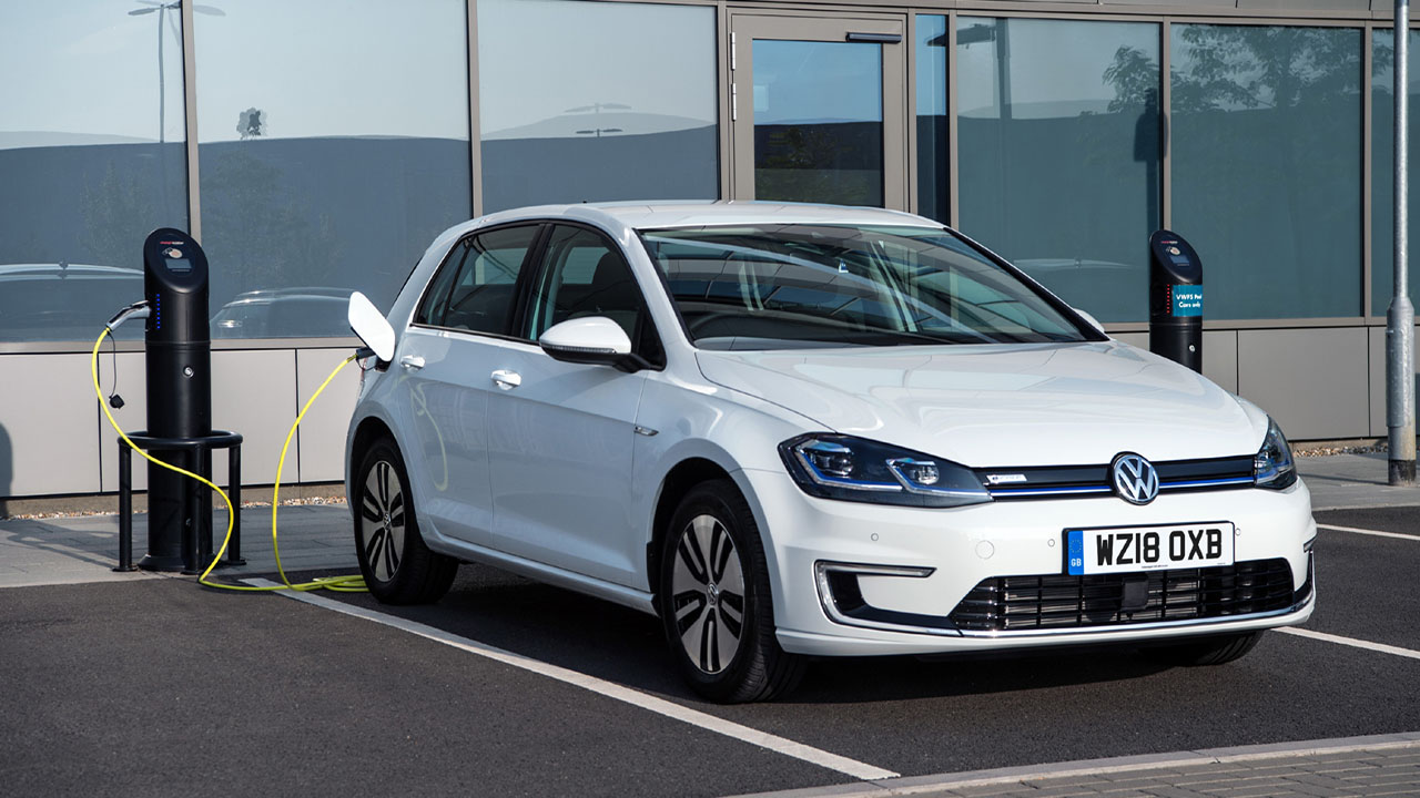 White Volkswagen e-Golf, plugged into charging point