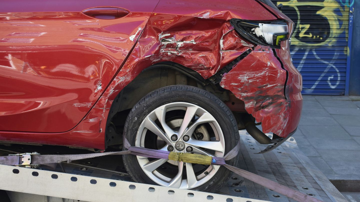 Red car that had its rear end hit, is being towed.