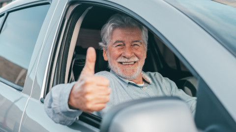 Elderly Male Driver Sticking His Thumb Up Out of the Car Window