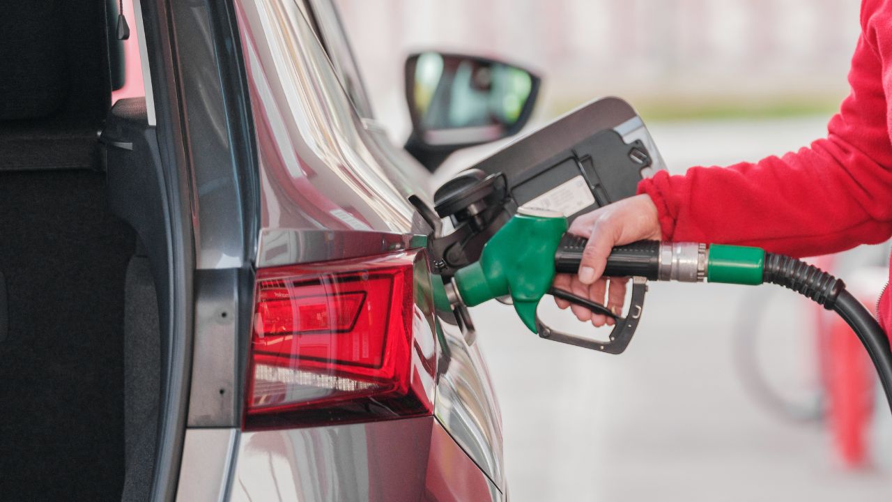 Woman wearing a red jacket putting fuel in her silver car
