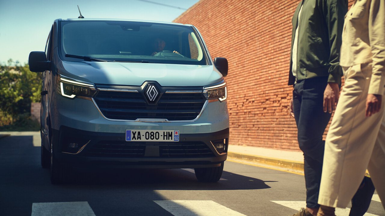 Blue Renault Trafic with passengers crossing road