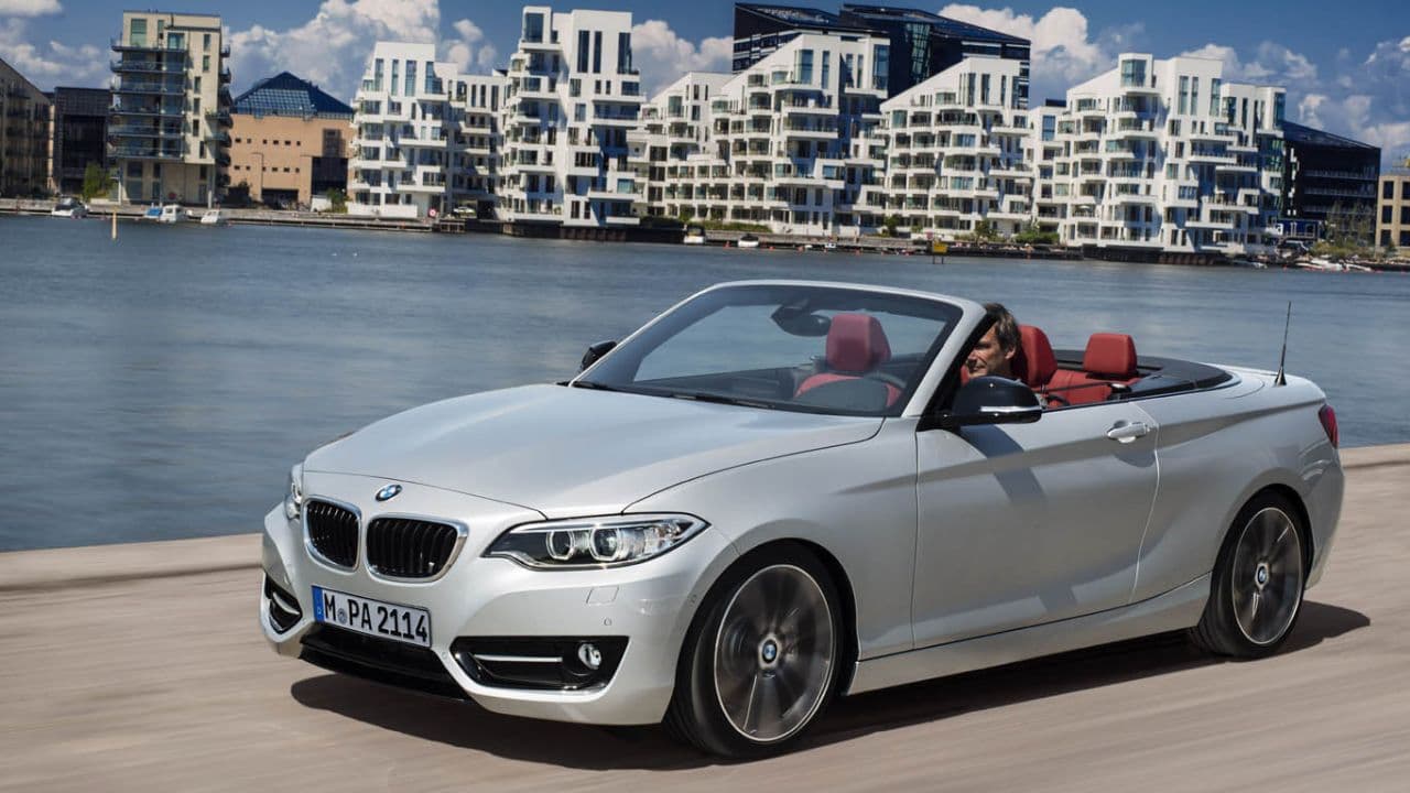 Silver BMW 2 Series Convertible driving by the ocean with beach flats in the background