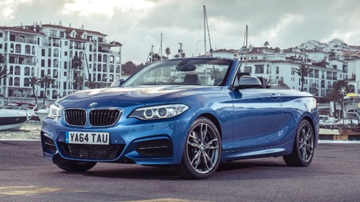 Blue BMW 2 Series Convertible parked in front of the ocean with beach flats in the background