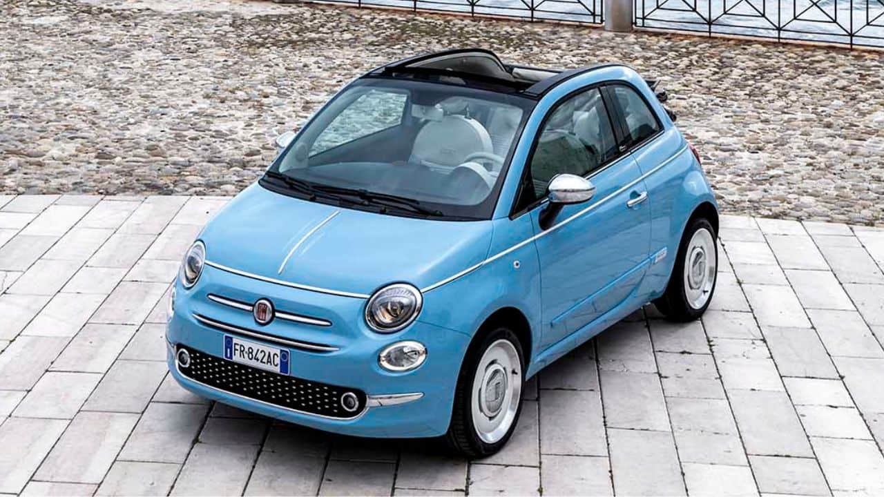Blue Fiat 500c parked in front of a stone wall