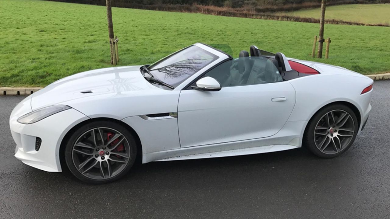 White Jaguar F-TYPE parked in front of a grass field