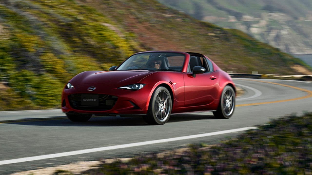 Red Mazda MX5 driving in the mountain on a sunny day