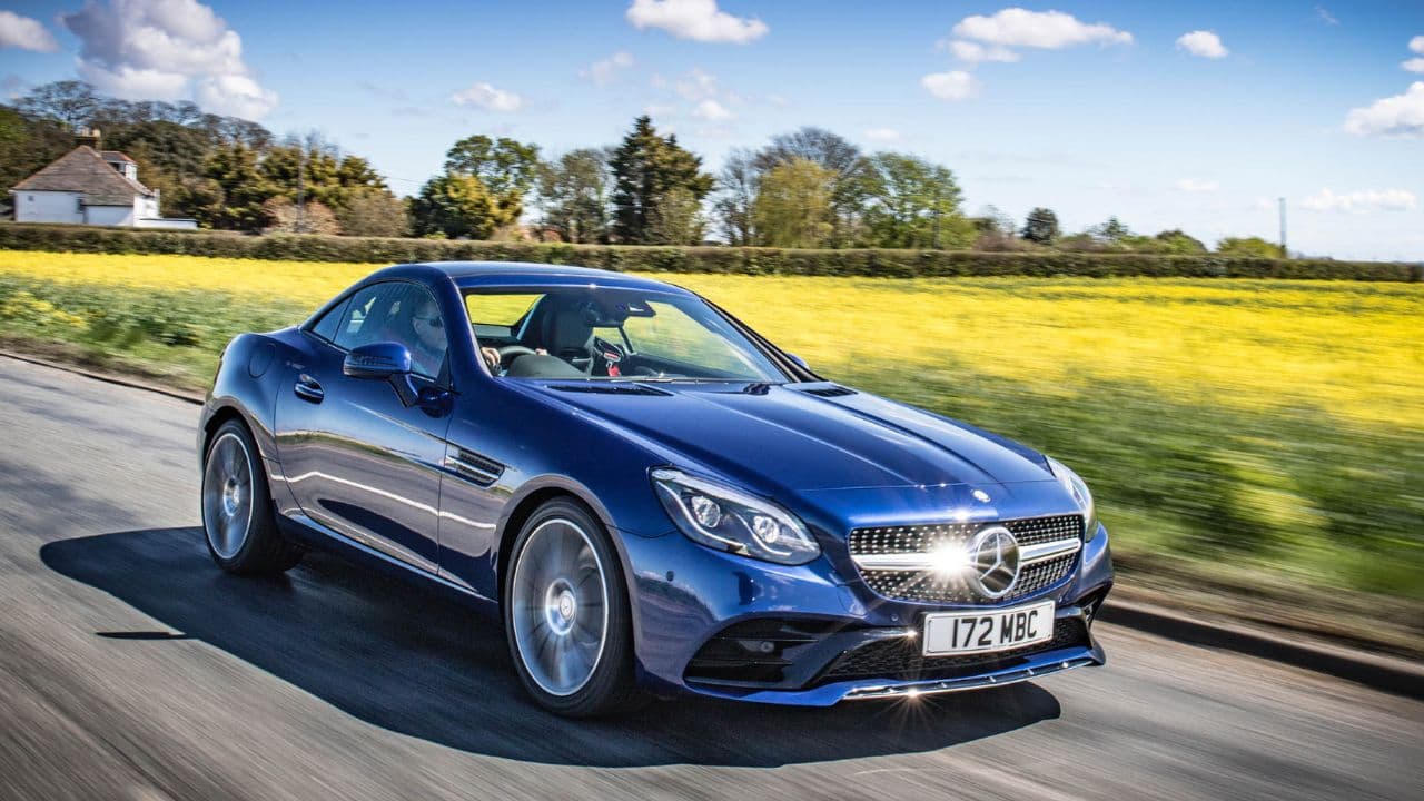 Blue Mercedes-Benz SLC driving besides a grass field on a sunny day