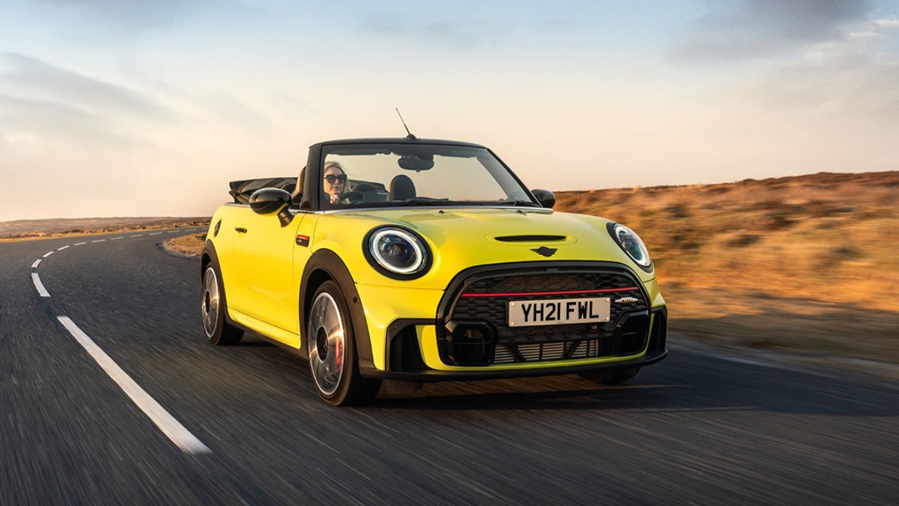 Yellow MINI convertible driving by a field of dried out grass