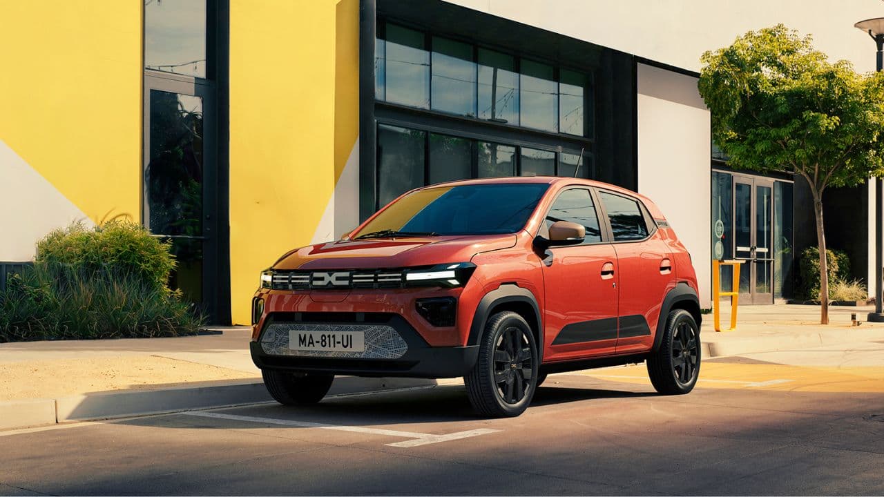 Orange Dacia Spring parked in front of a yellow building