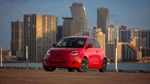 Red Fiat 500e parked in front of a large city skyline