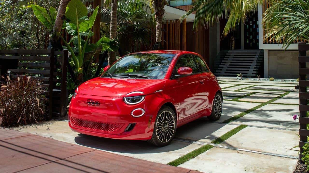 Red Fiat 500e parked in front of a house full of trees