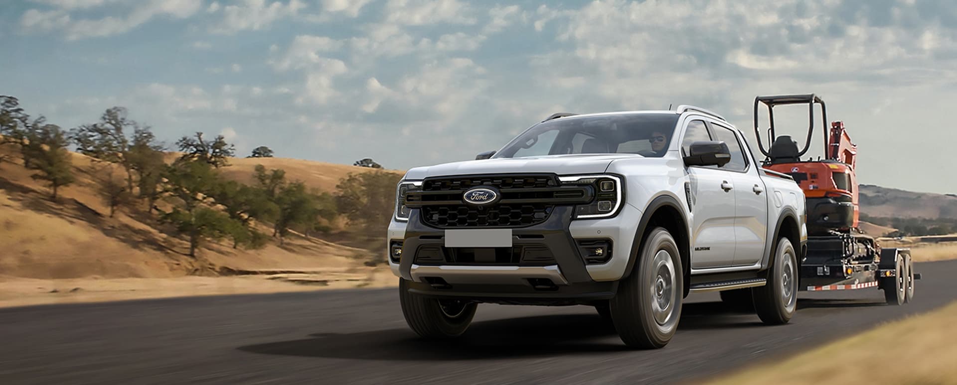 White Ford Ranger towing a small trailer with light machinery on