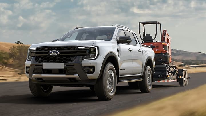 White Ford Ranger towing a small trailer with light machinery on