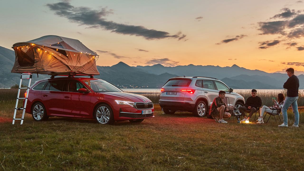 Red Skoda Octavia with roof tent fitted with people around campfire