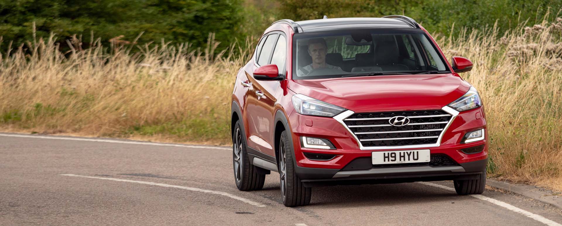 Red Hyundai Tucson driving in the countryside