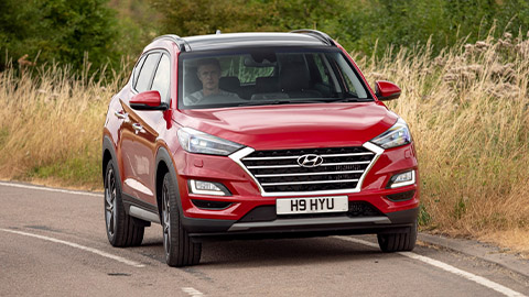 Red Hyundai Tucson driving in the countryside