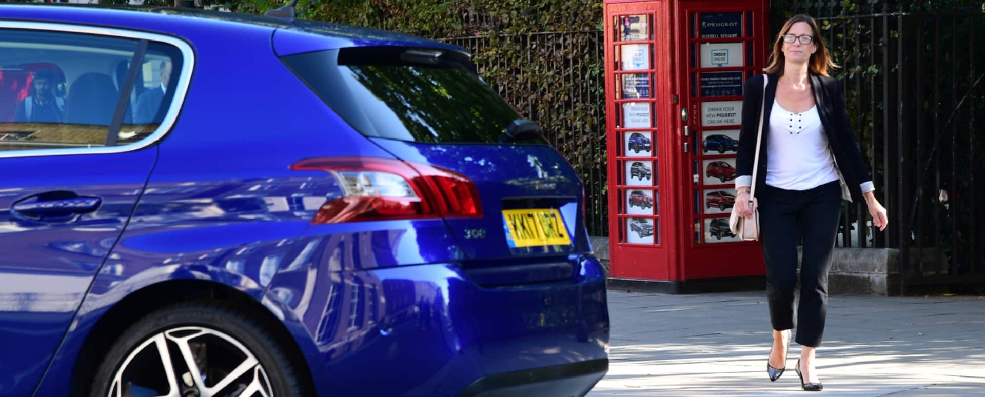 Woman walking up to a blue car