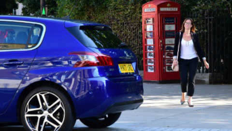 Woman walking up to a blue car