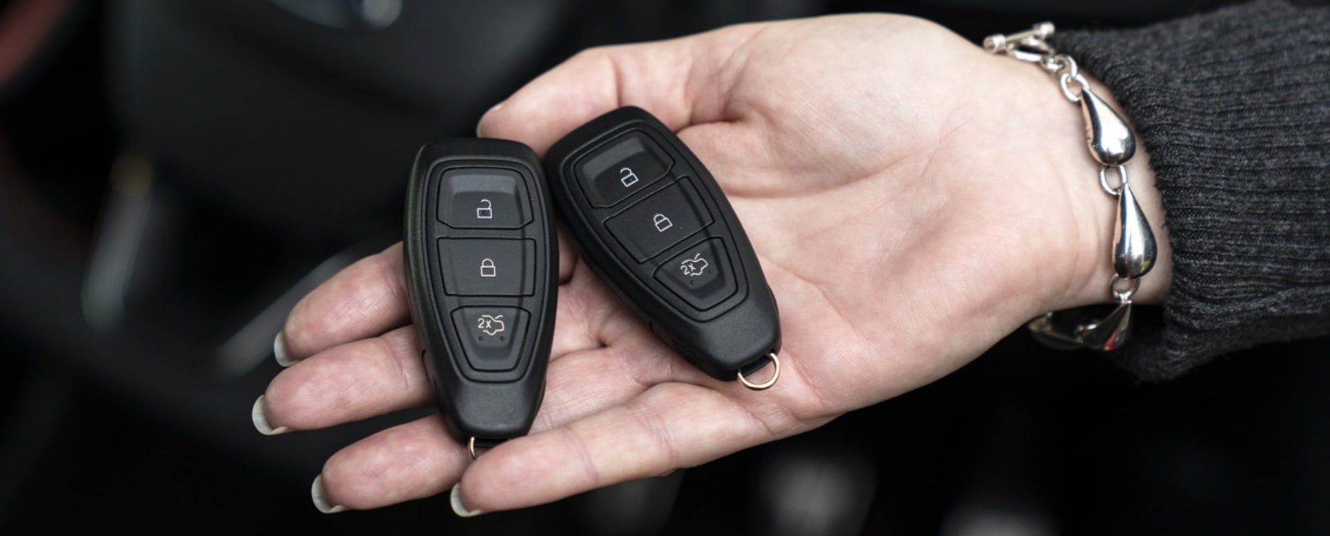 A woman holding two car fobs