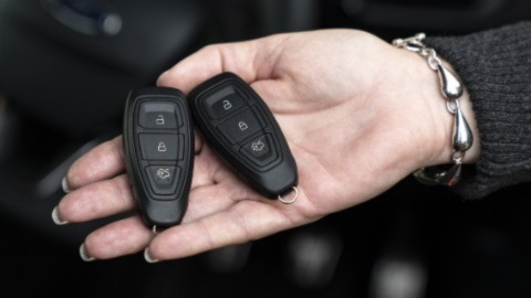 A woman holding two car fobs