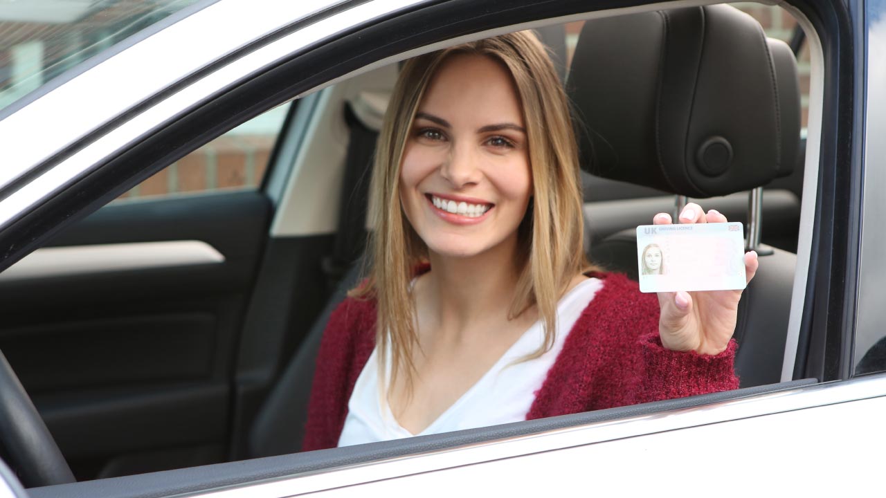 A woman showing her drivers license through a car window