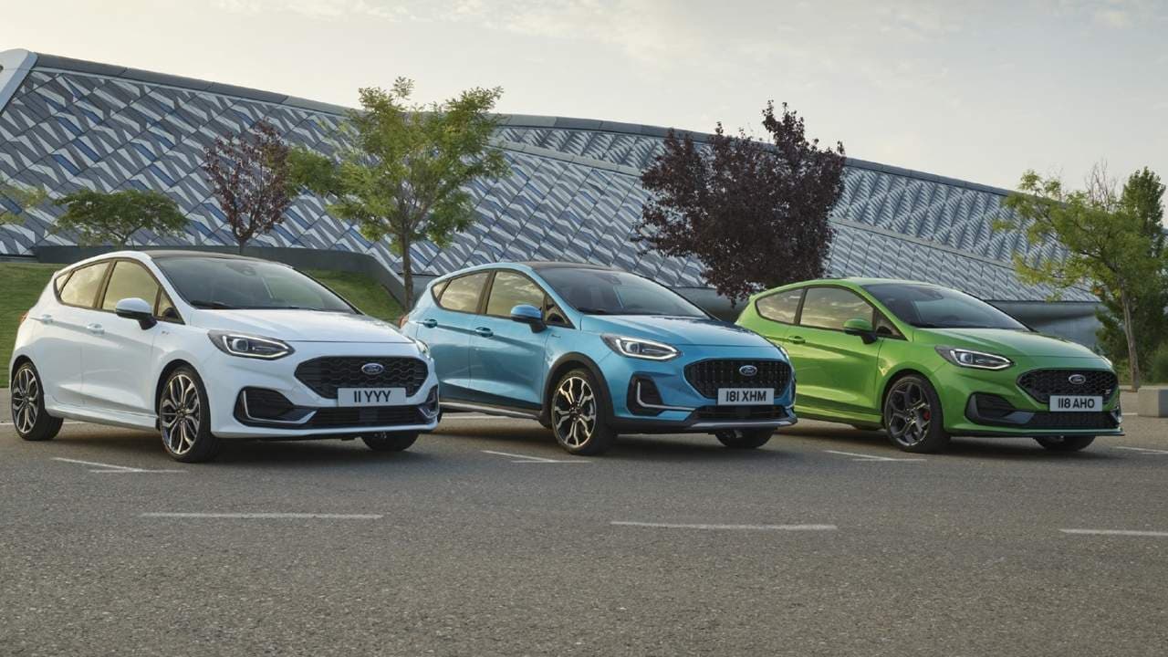 White, blue and green Ford Fiestas parked side by side