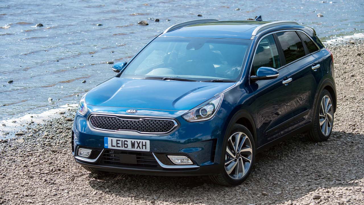 Blue Kia Niro hybrid, parked next to country lake