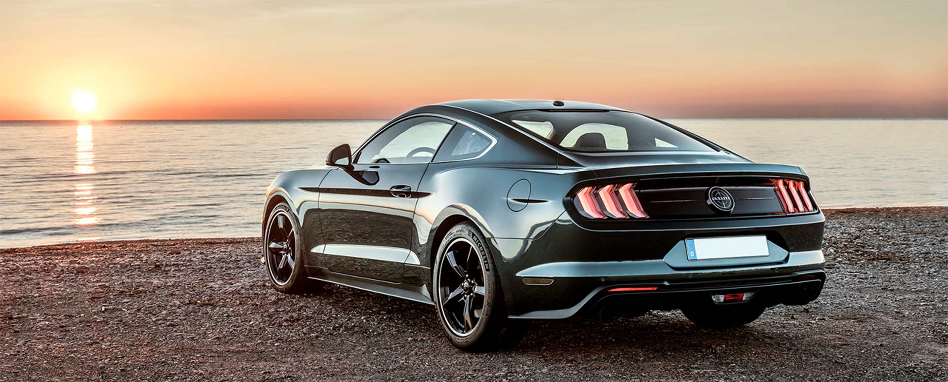 green bullitt ford mustang facing sunset