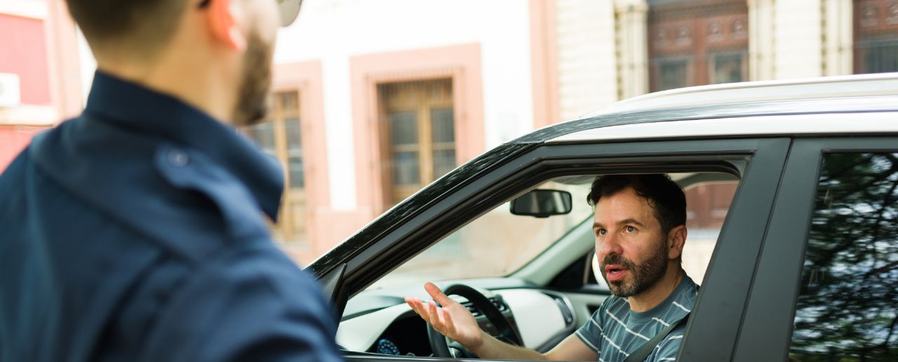 Police officer arguing with a man who is sitting inside of his car