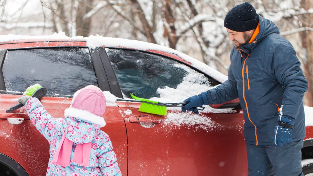 Father and Daughter Clearing Snow Off Car