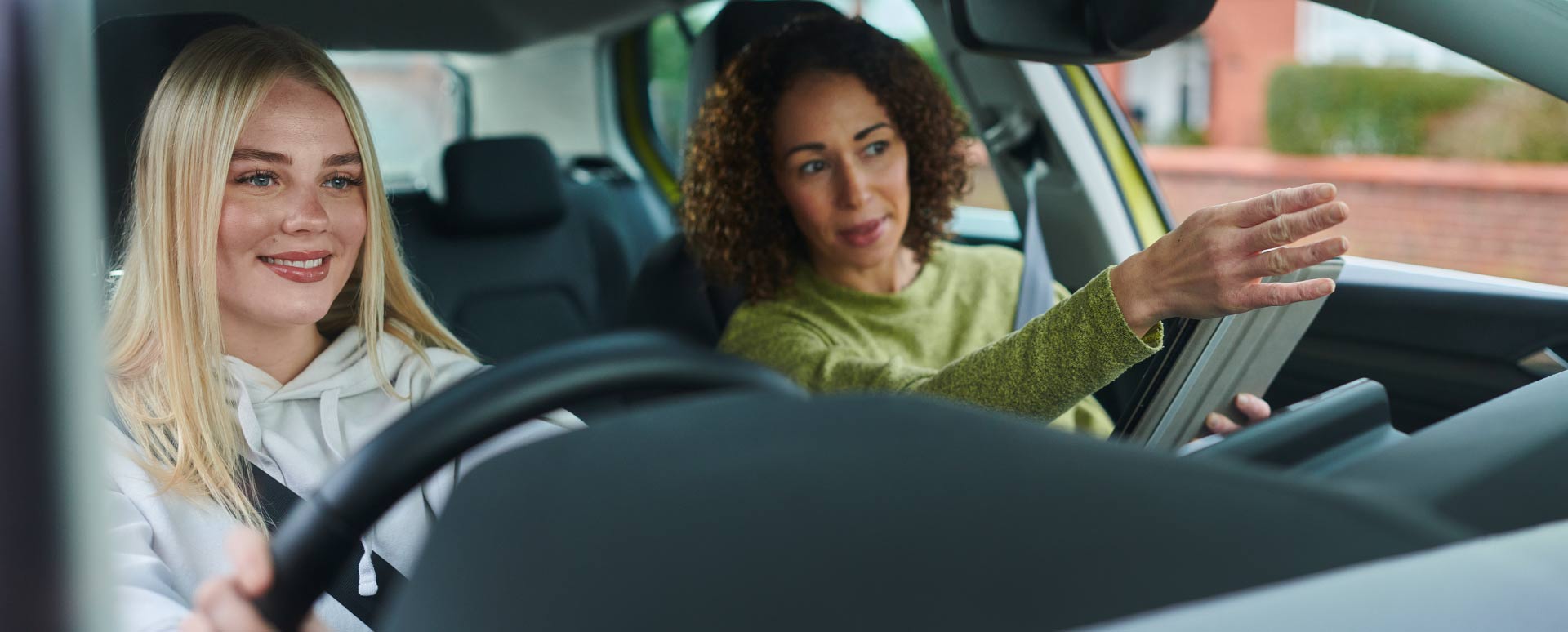 Driving instructor guiding learner driver during lesson inside car