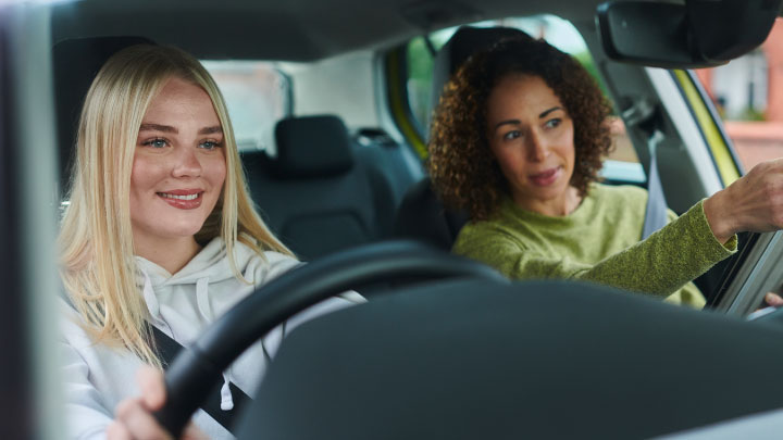 Driving instructor guiding learner driver during lesson inside car