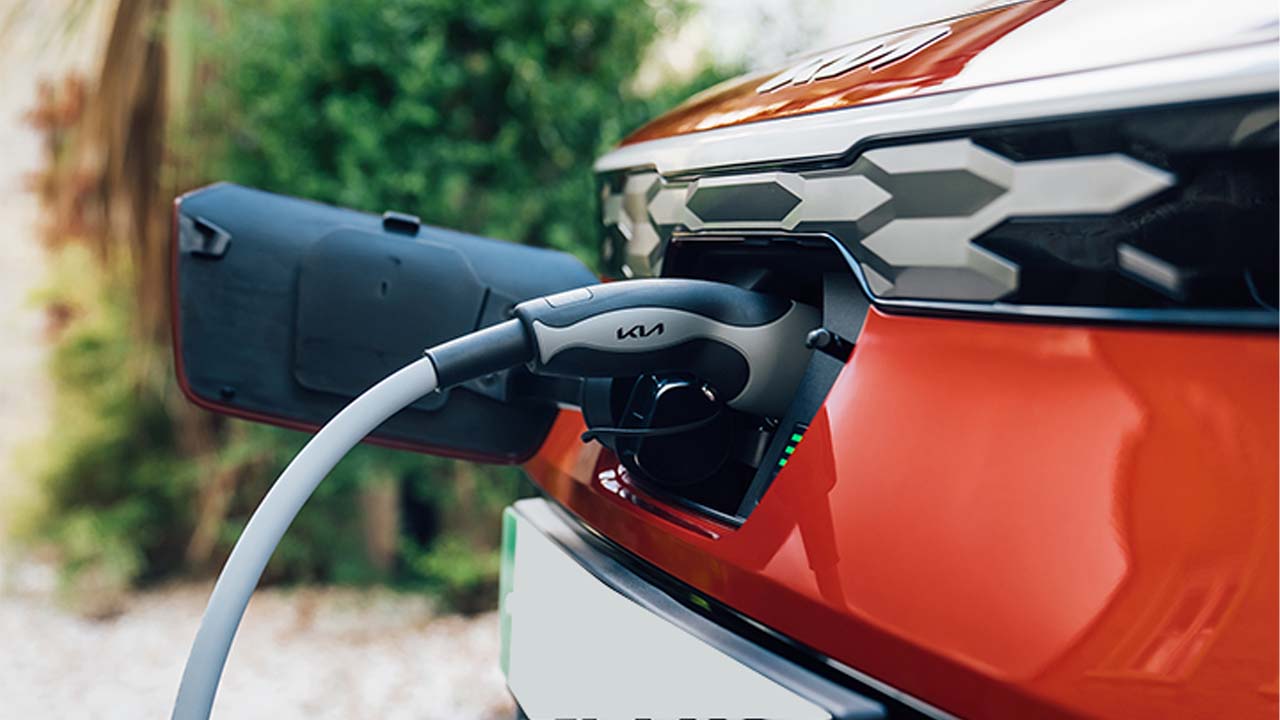 Red Kia Niro, charging via port in front grille