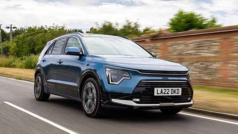 Blue Kia Niro, motion driving shot, brick wall in the background