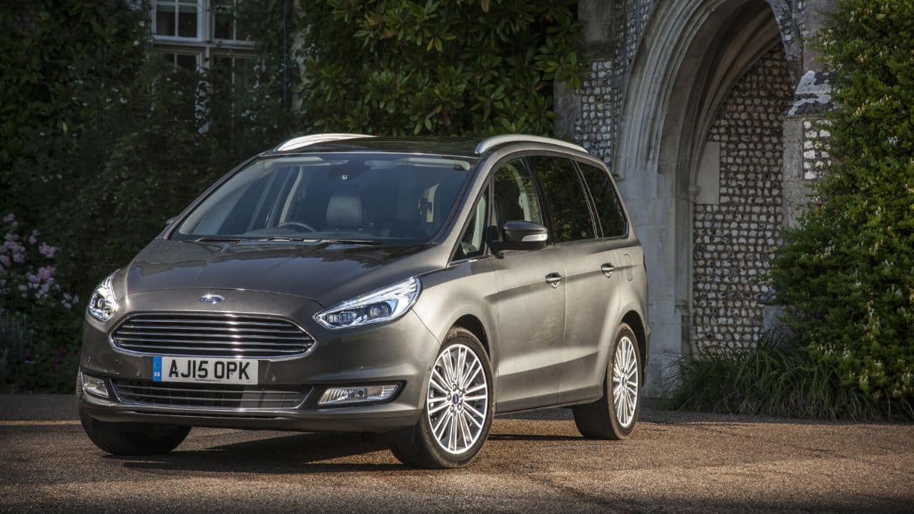 Grey Ford Galaxy parked in front of a building covered with plants