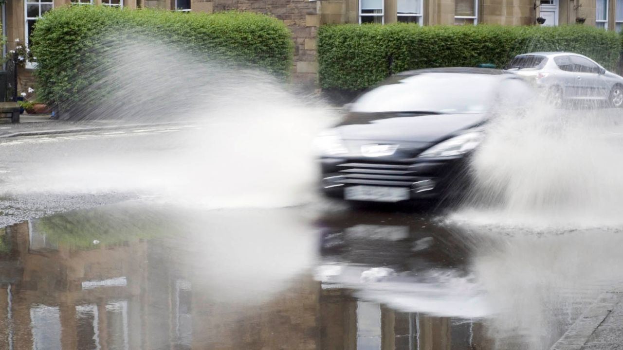 A black Peugeot driving through a puddle