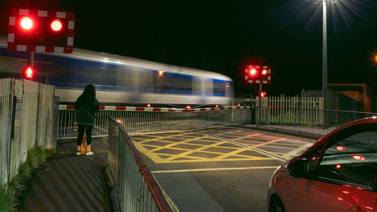 Red car waiting the train at level crossing
