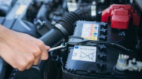 Man Unscrewing Battery in Car