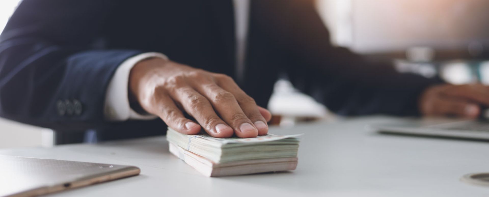 Man with hand on a pile of cash