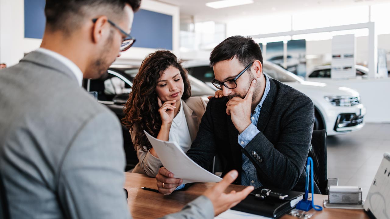 Man and woman reading a contract in a car dealership