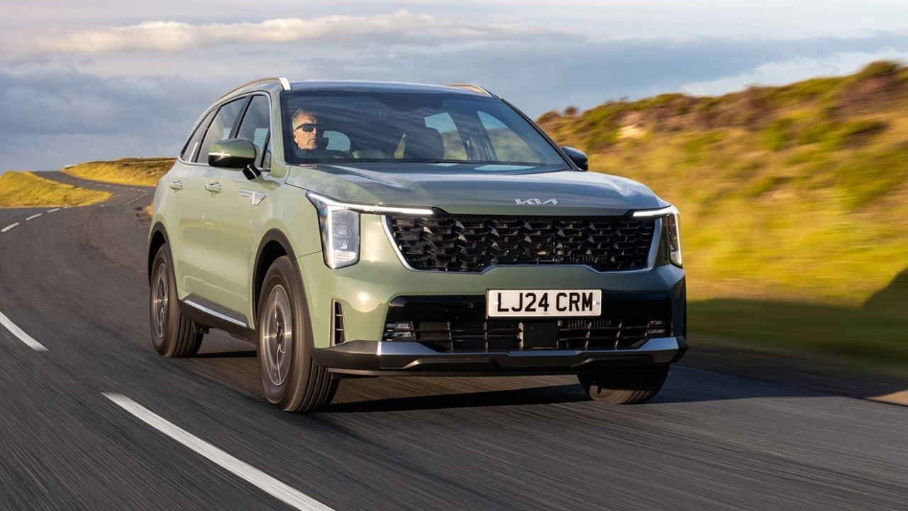 Green Kia Sorento driving in the countryside