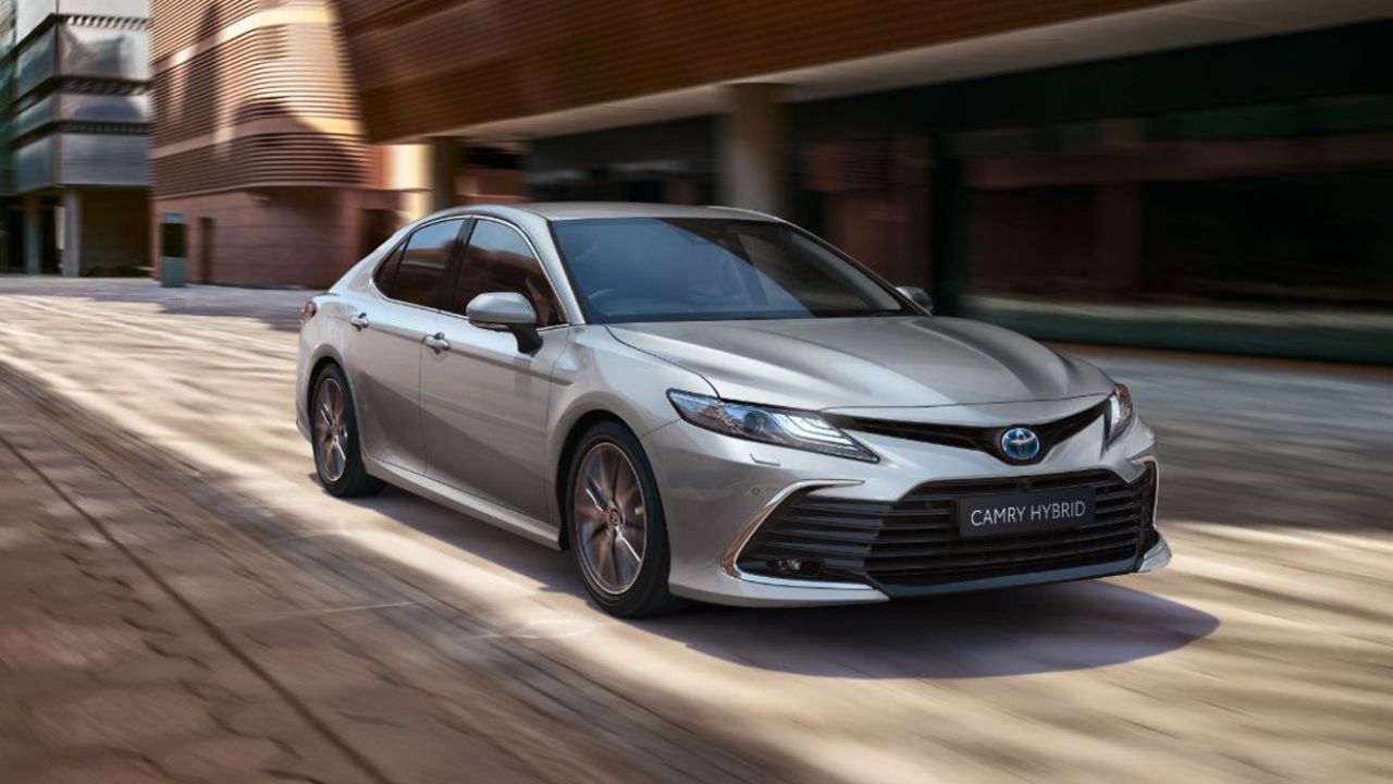 Toyota Camry driving in front of a brick building
