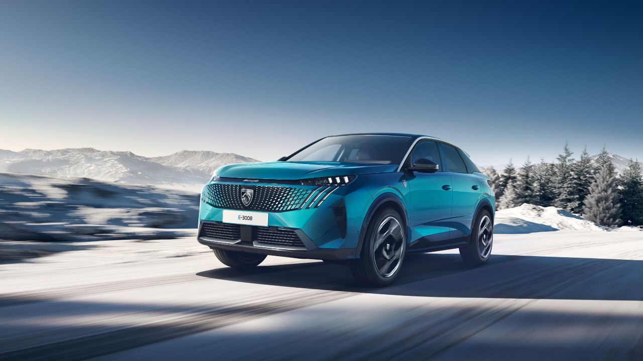 Front three-quarter view of a Peugeot E-3008 driving through a snowy mountain landscape