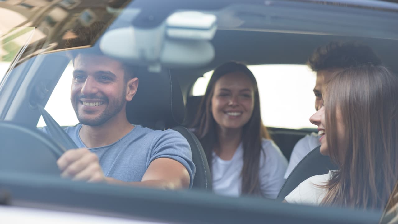 Smiley man driving two ladies