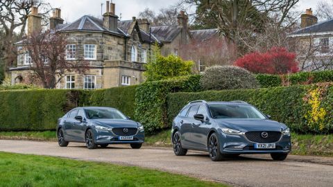 A couple of Mazda 6 driving on the road with beautiful British houses in the background